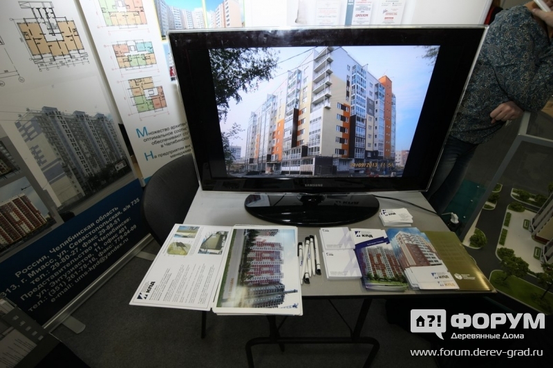 Панельный дом и реклама на стенде Миасского завода крупнопанельного домостроения